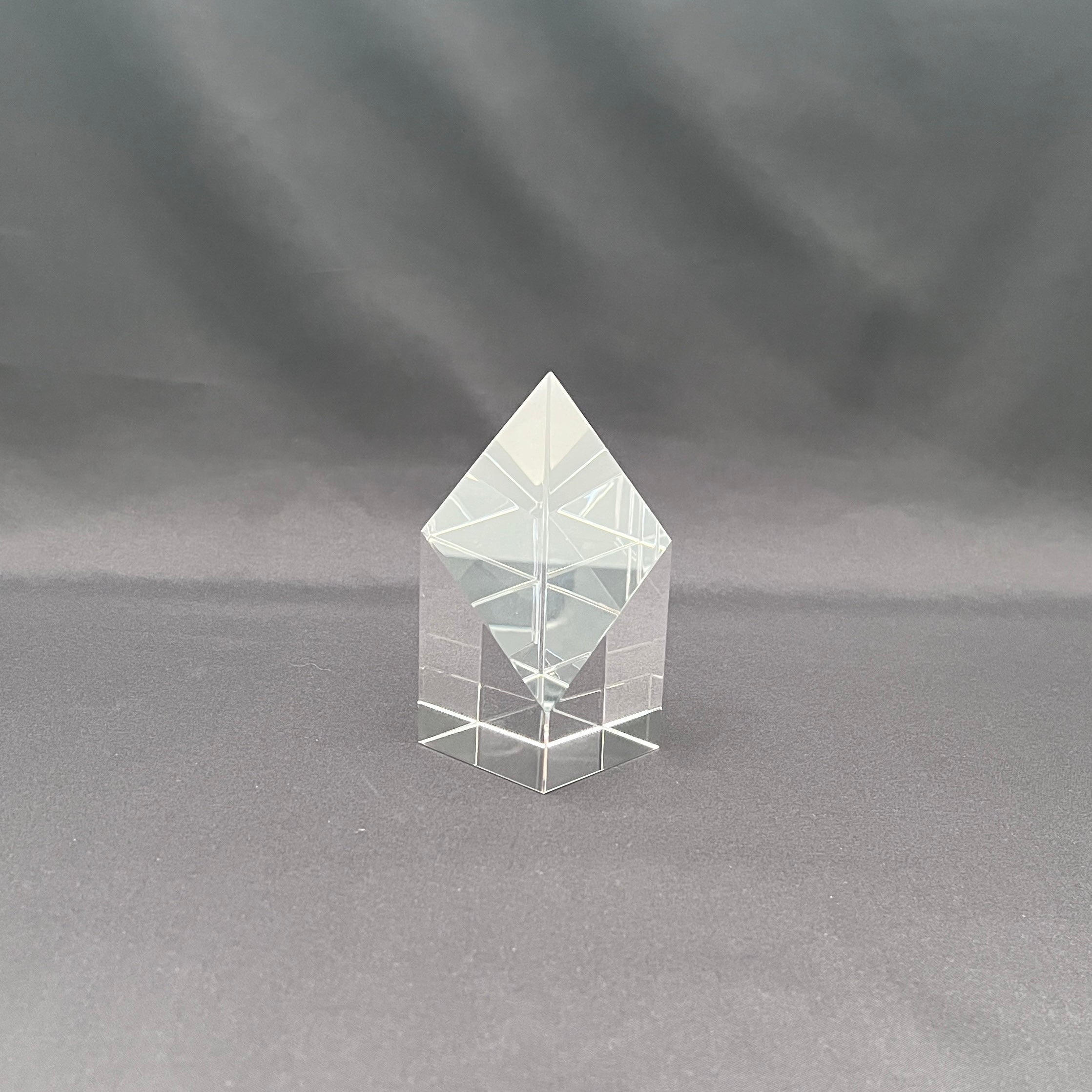 A clear acrylic geometric crystal tower with a diamond-shaped top and a multi-tiered square base,