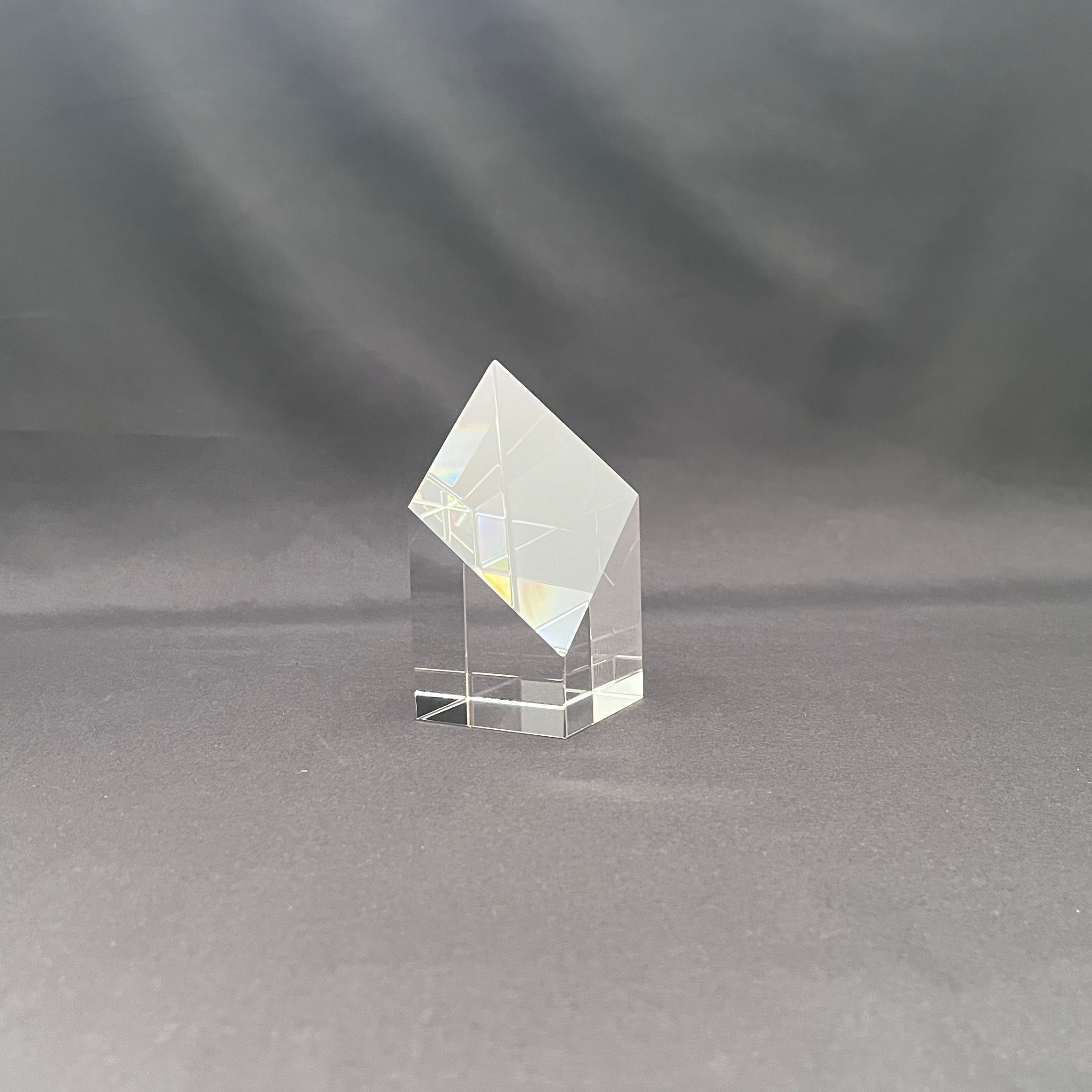 A clear crystal or glass geometric crystal tower with a diamond-shaped top and a square base.