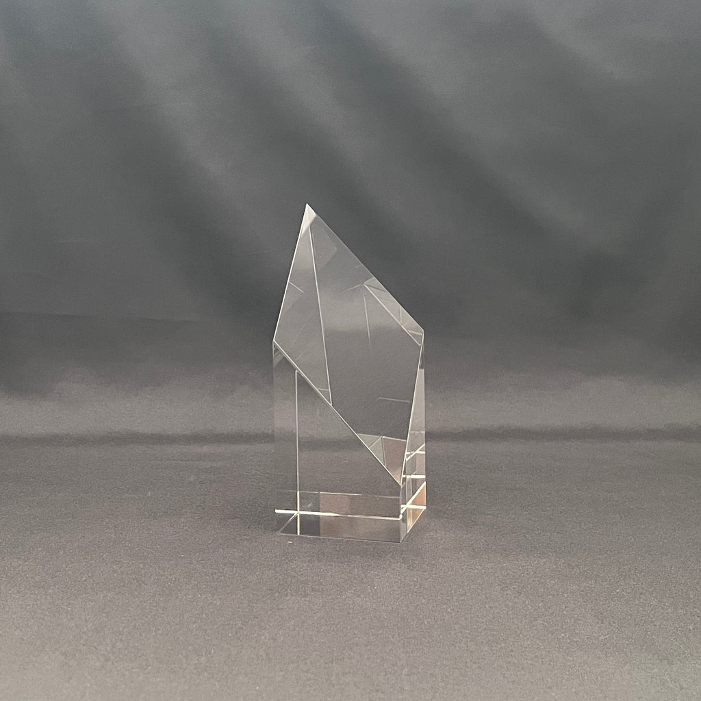 A clear acrylic or glass geometric trophy award stand with a faceted crystal-like design.