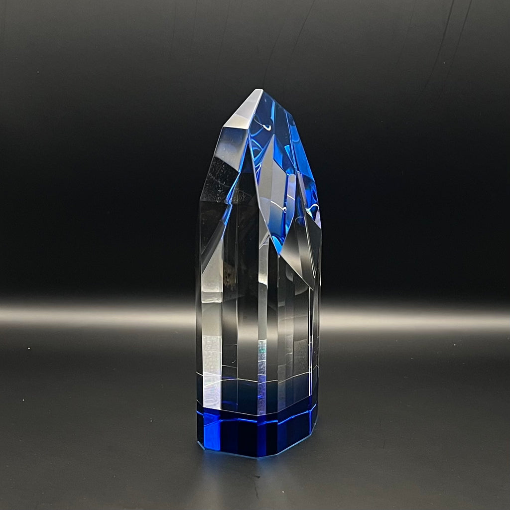 Crystal tower with blue and clear facets on a dark background