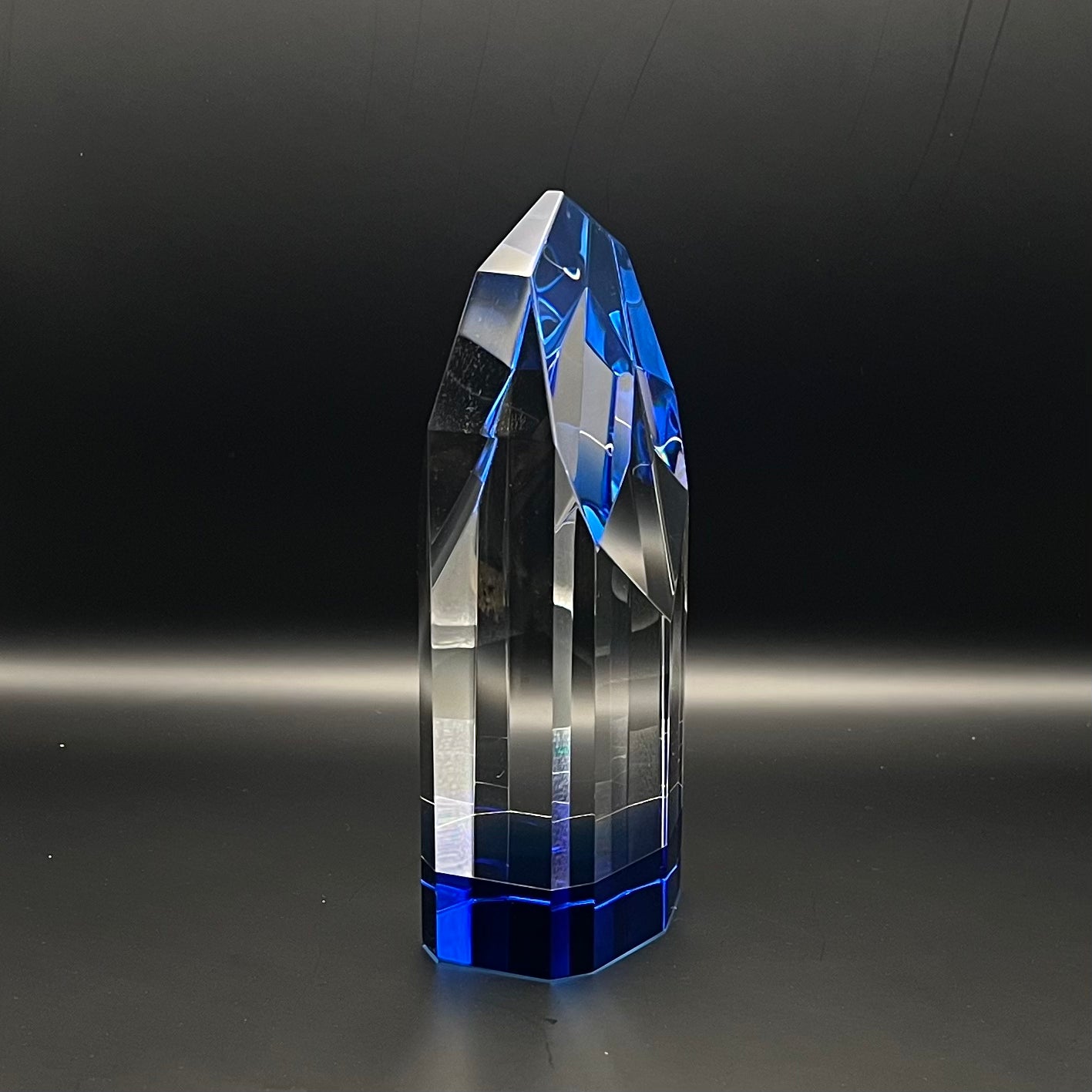 Crystal tower with blue and clear facets on a dark background