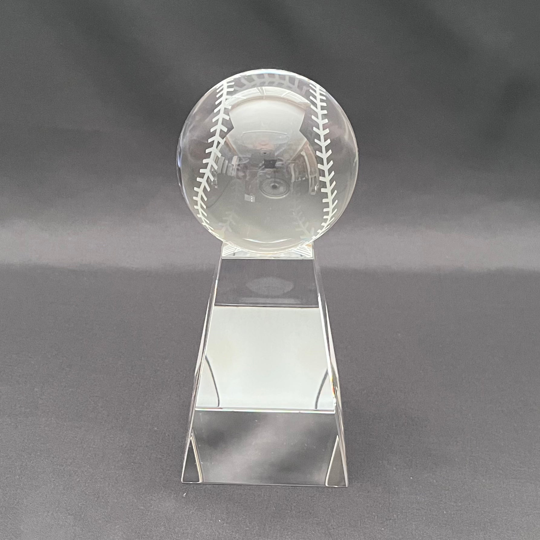 A clear crystal baseball trophy on a base 