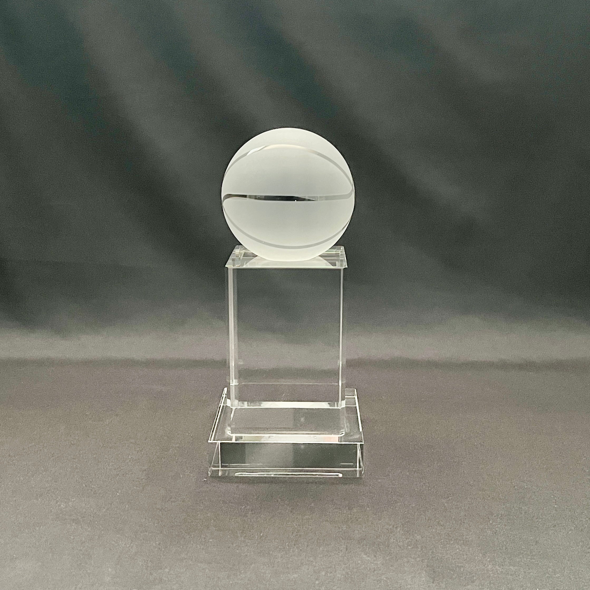 A clear acrylic trophy display stand featuring a frosted white crystal basketball on top.