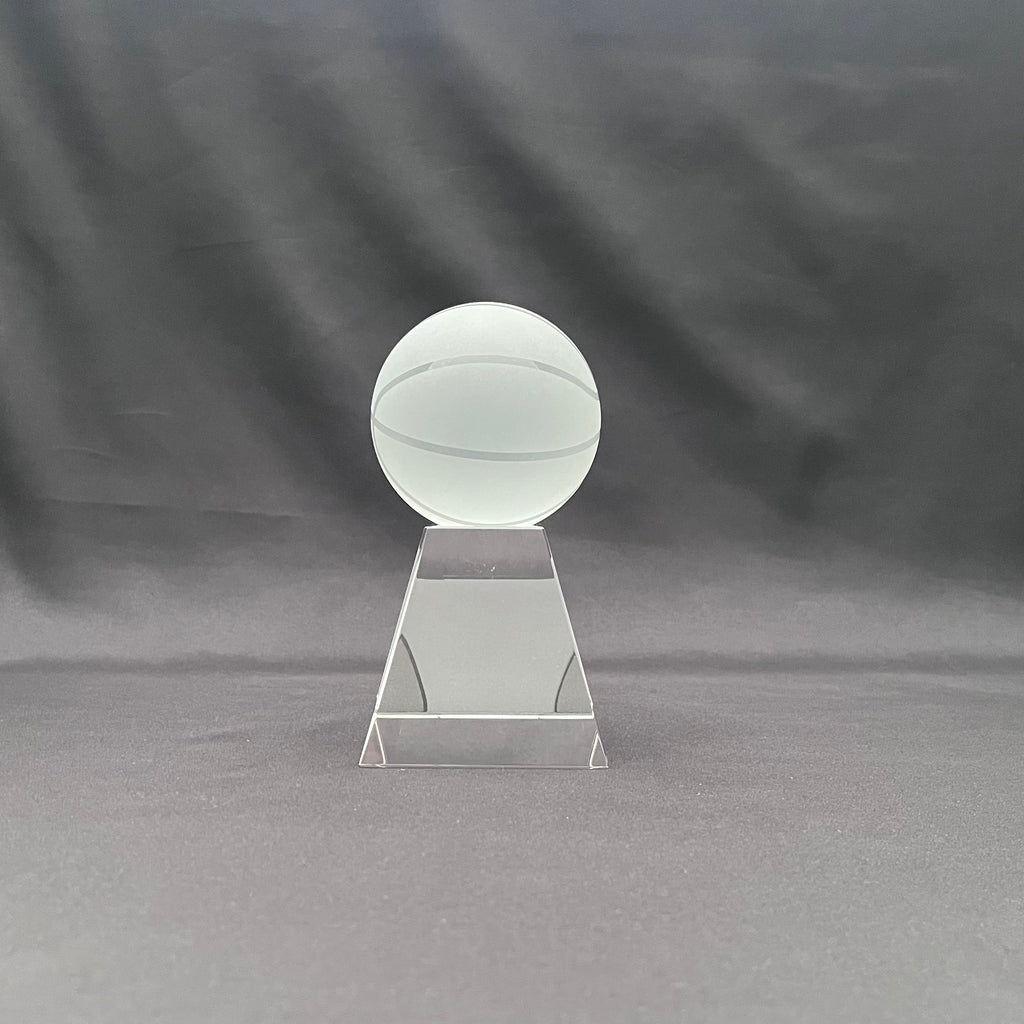 A clear acrylic trophy or award plaque featuring a frosted glass or acrylic basketball on a tiered rectangular base.