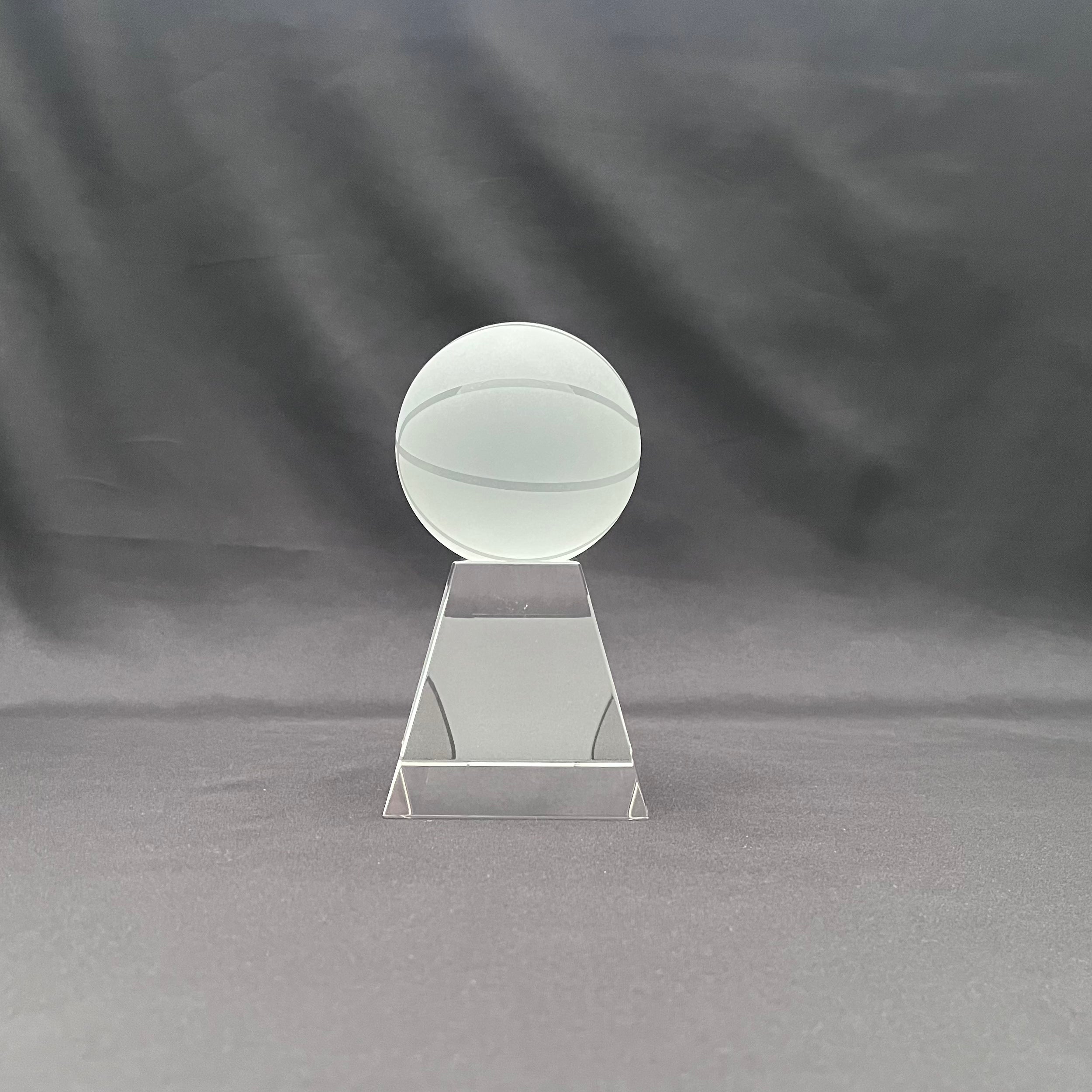 A clear acrylic trophy or award plaque featuring a frosted glass or acrylic basketball on a tiered rectangular base.