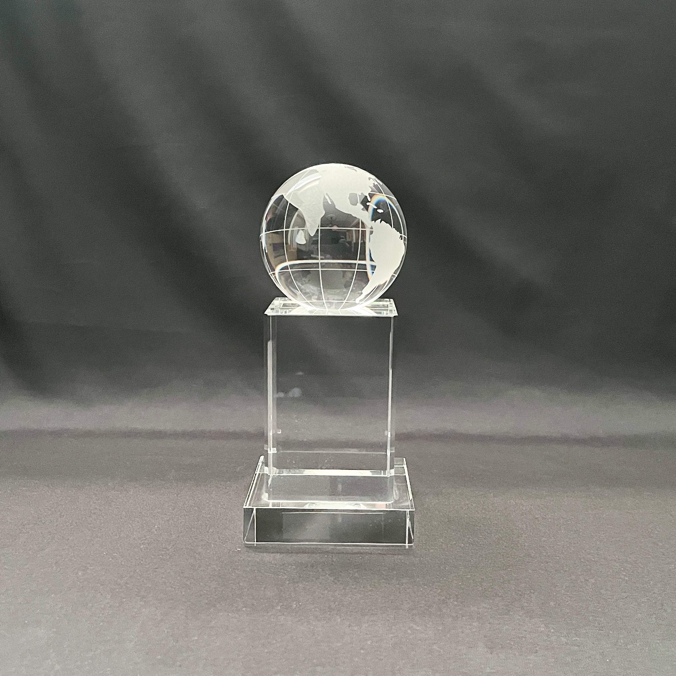 A clear crystal globe trophy on a matching rectangular pedestal base, 