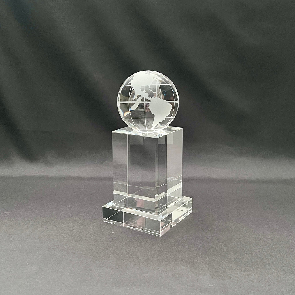 A clear acrylic or glass trophy featuring an etched globe on top of a rectangular pedestal base.