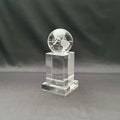 A clear acrylic or glass trophy featuring an etched globe on top of a rectangular pedestal base.