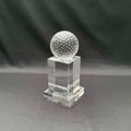 A clear crystal trophy stand featuring a textured, dimpled golf ball on top