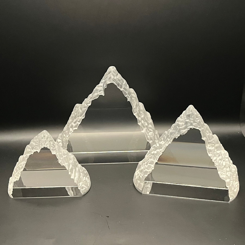 Set of three Everest sculptures on a reflective surface with a dark background