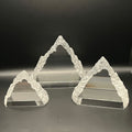 Set of three Everest sculptures on a reflective surface with a dark background