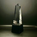 Crystal obelisk on a black base against a dark background
