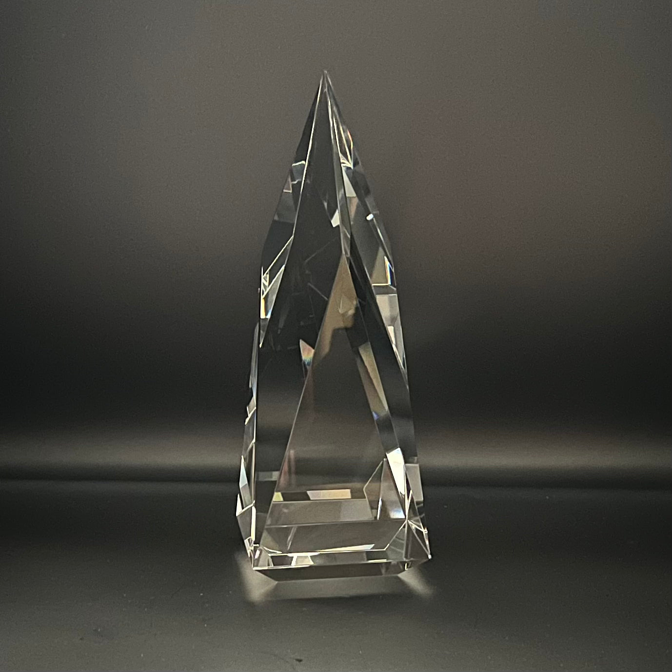Clear crystal pyramid-shaped trophy on a dark background