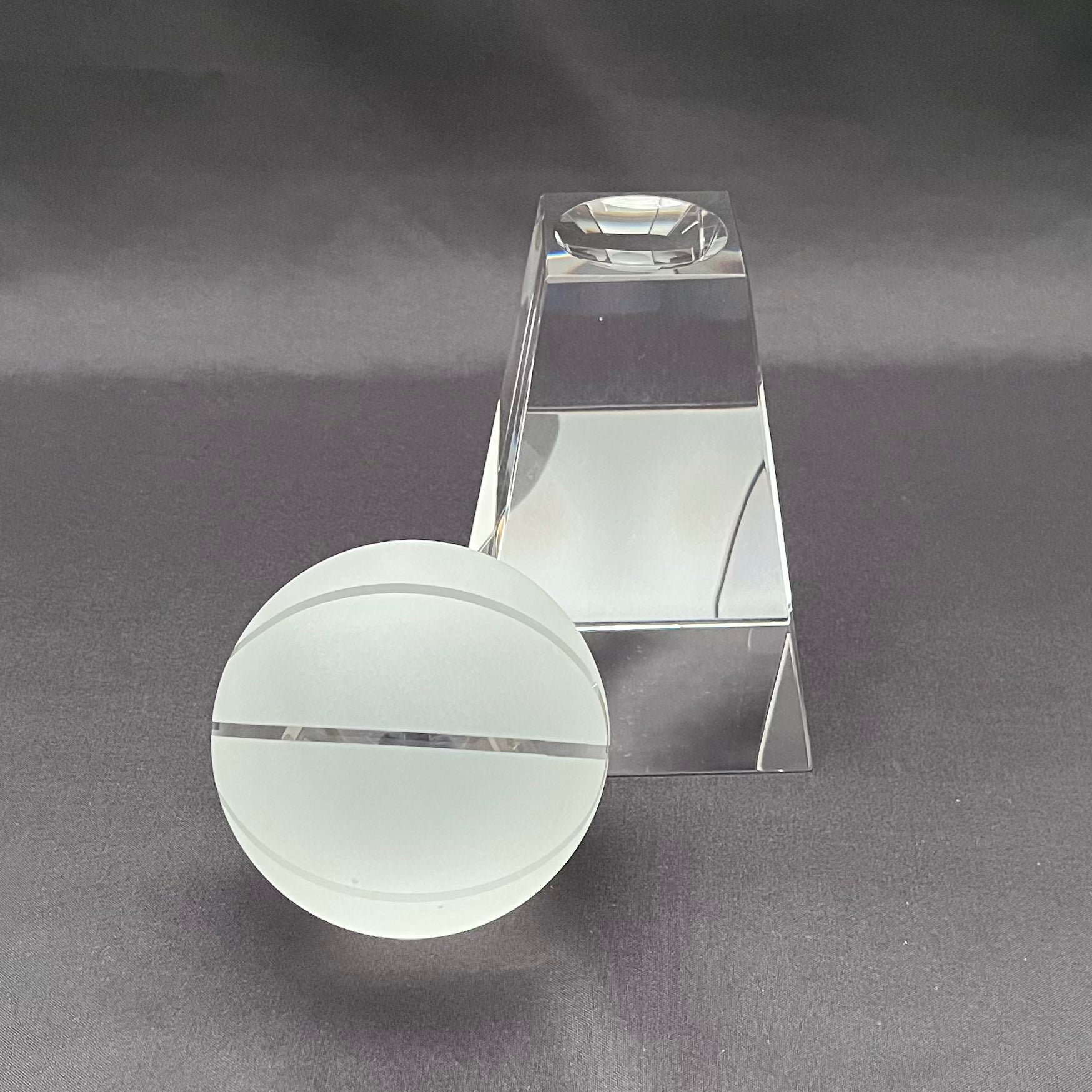 Clear acrylic or glass display stand with a circular base and a rectangular tower.