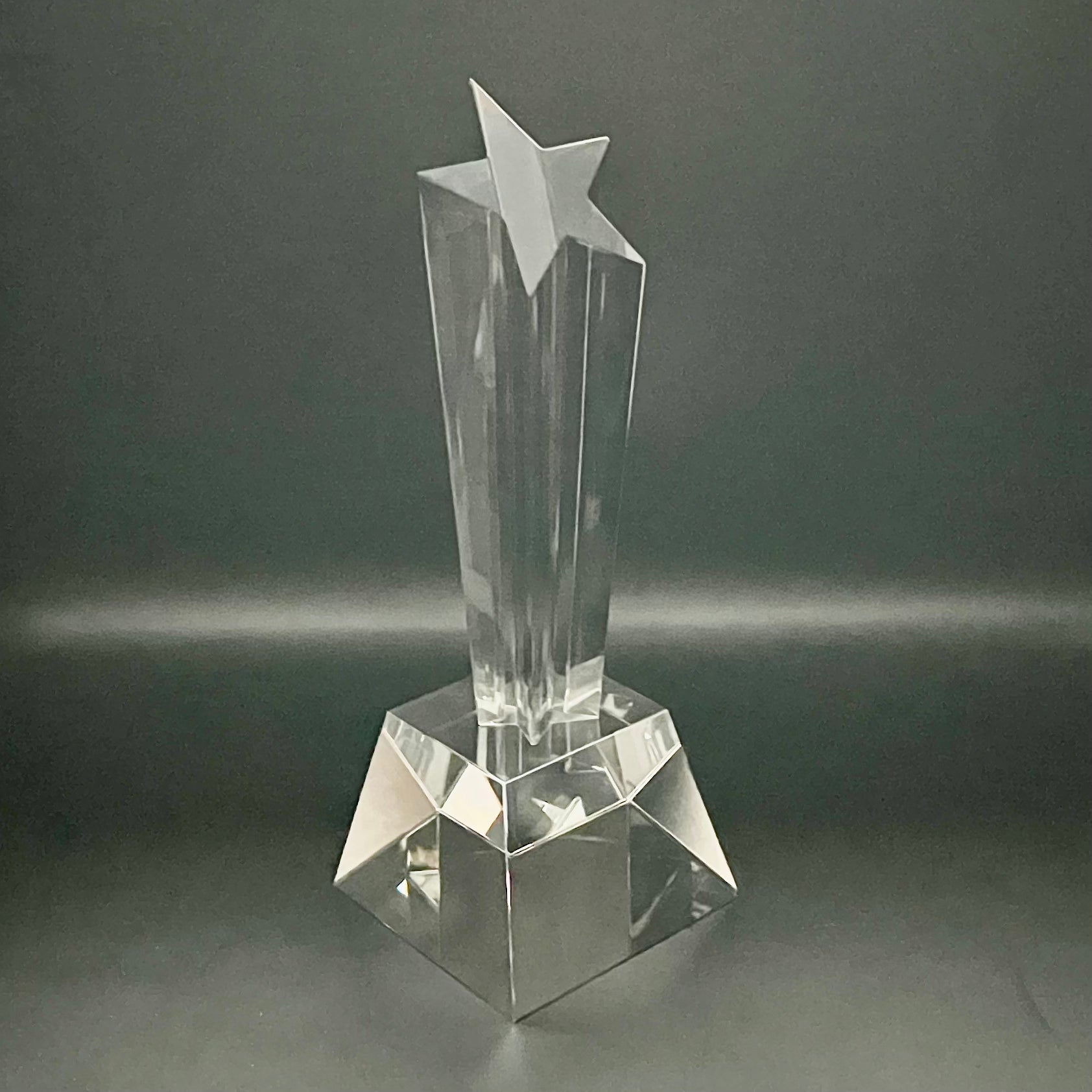 Clear crystal trophy with star design on a dark gray background
