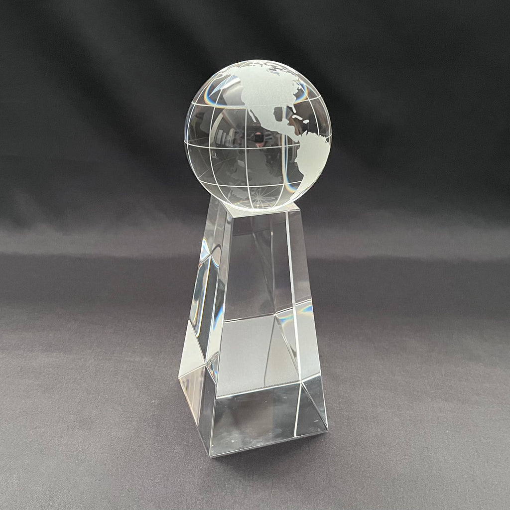 A clear glass or acrylic trophy-style globe on a faceted rectangular pedestal, 
