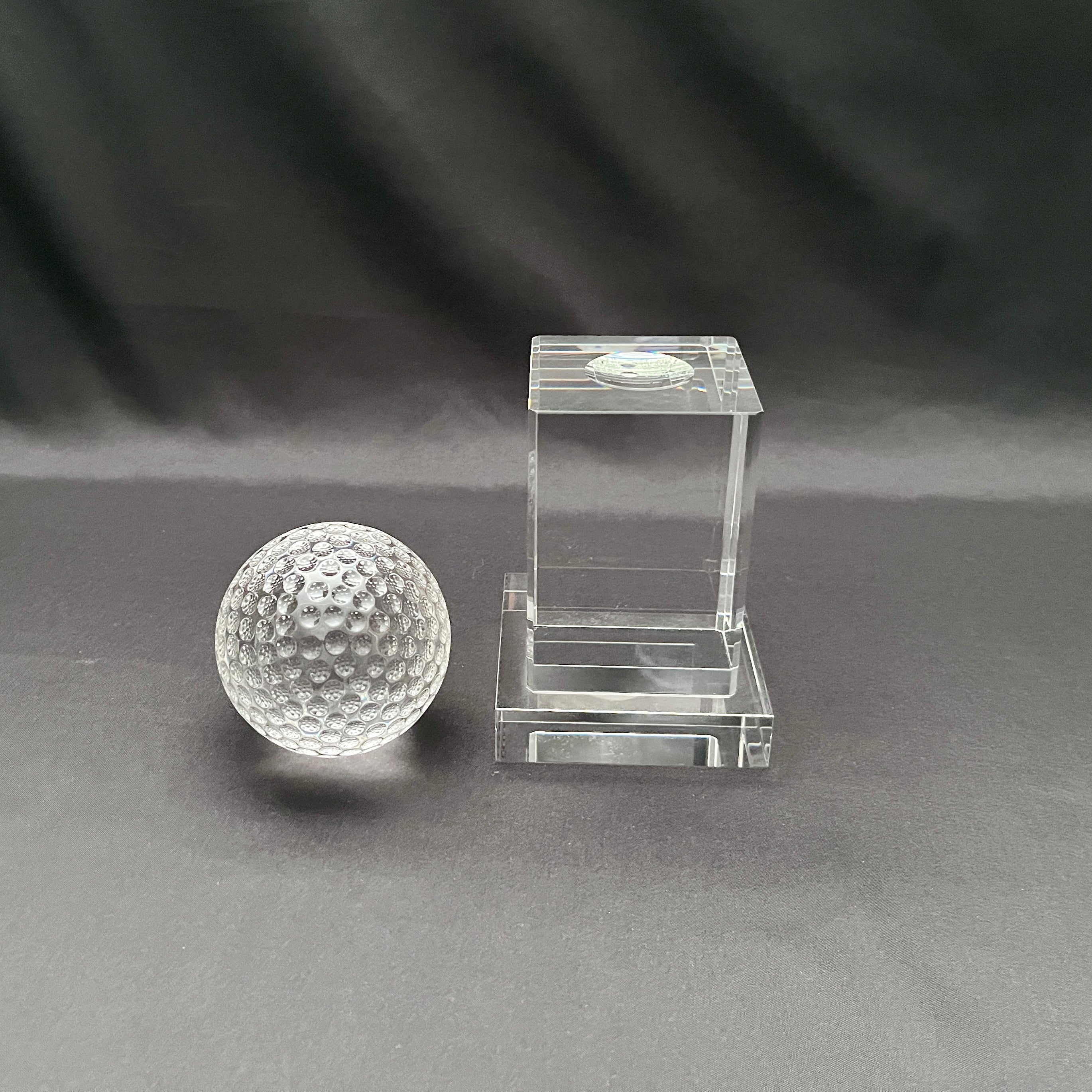 Clear acrylic paperweight set featuring a round glass-like sphere and a rectangular acrylic block on a dark gray background.