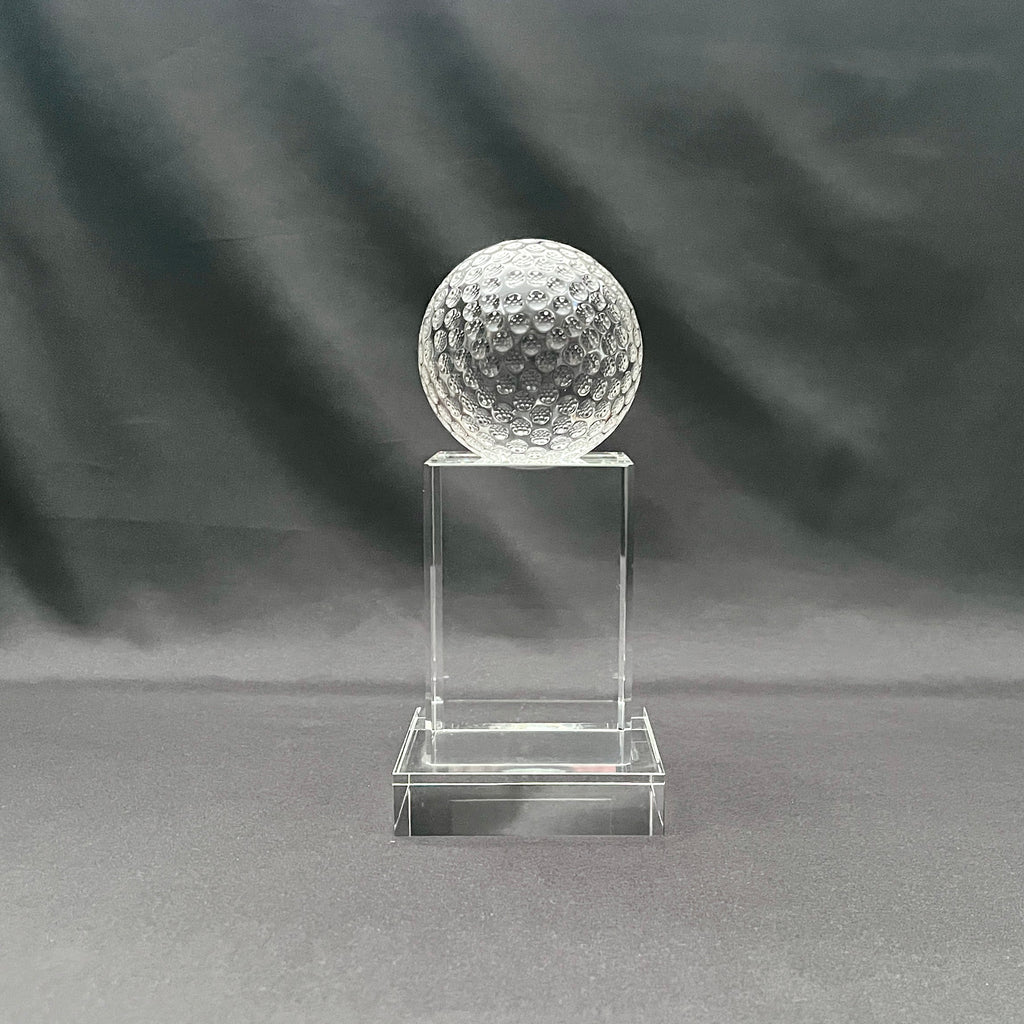 A clear crystal ball trophy display stand featuring a transparent golf ball on top of a rectangular pedestal.