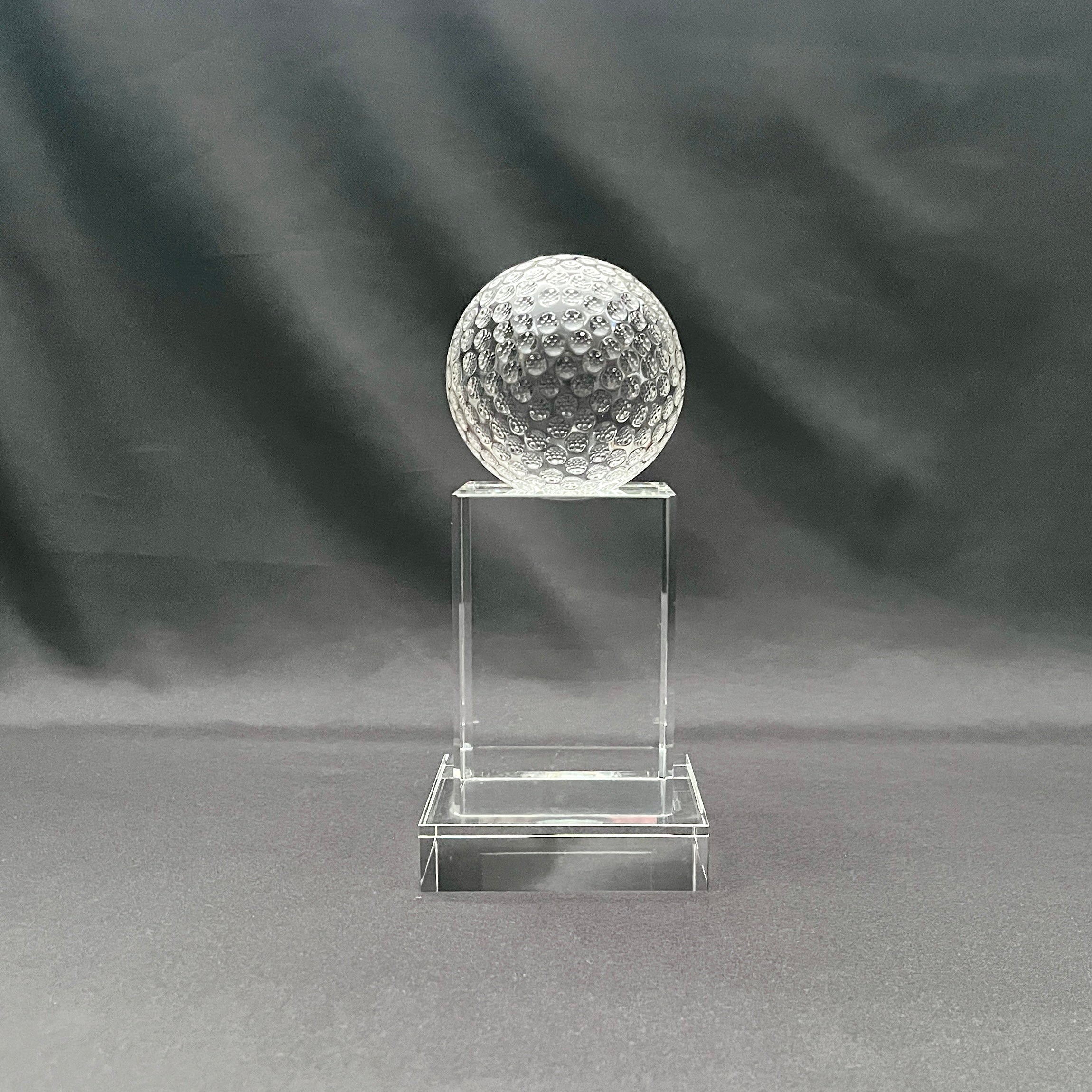 A clear crystal ball trophy display stand featuring a transparent golf ball on top of a rectangular pedestal.
