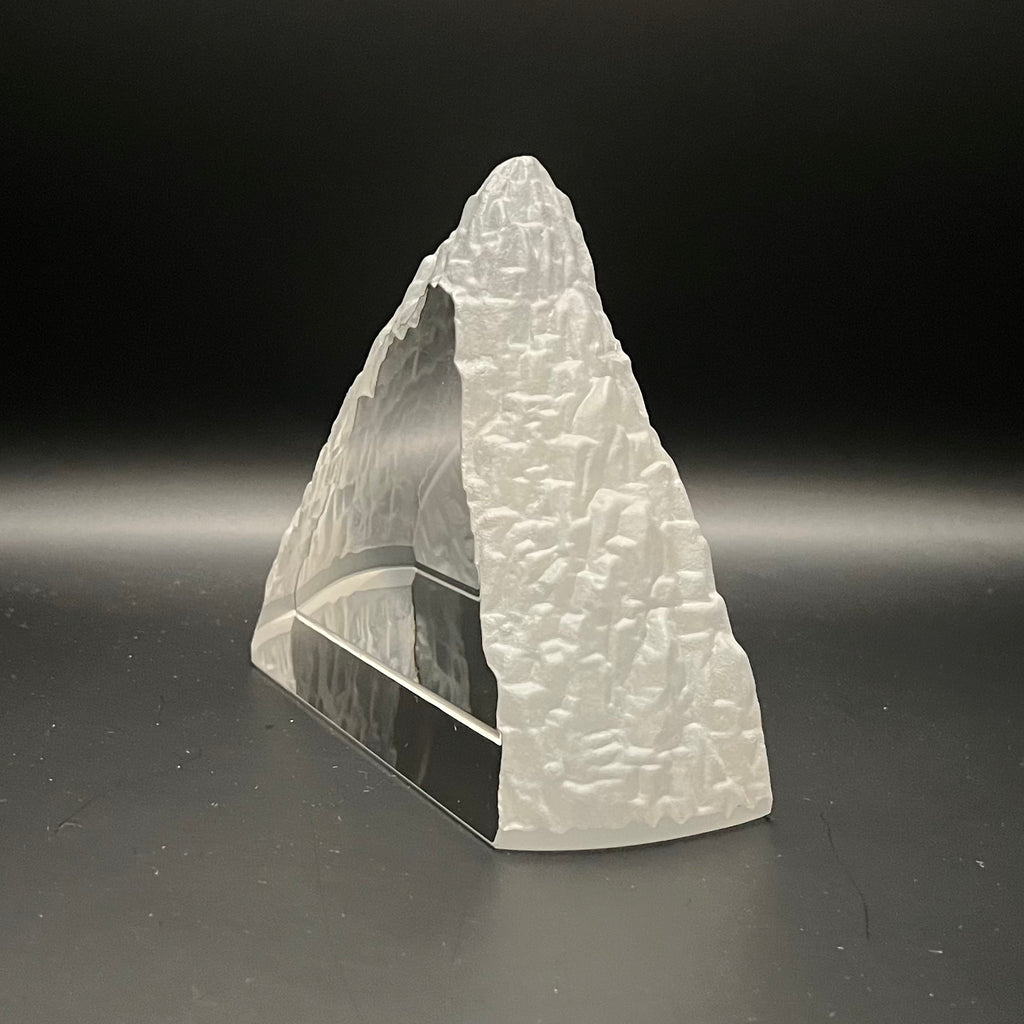 Glass mountain sculpture on a dark gray background
