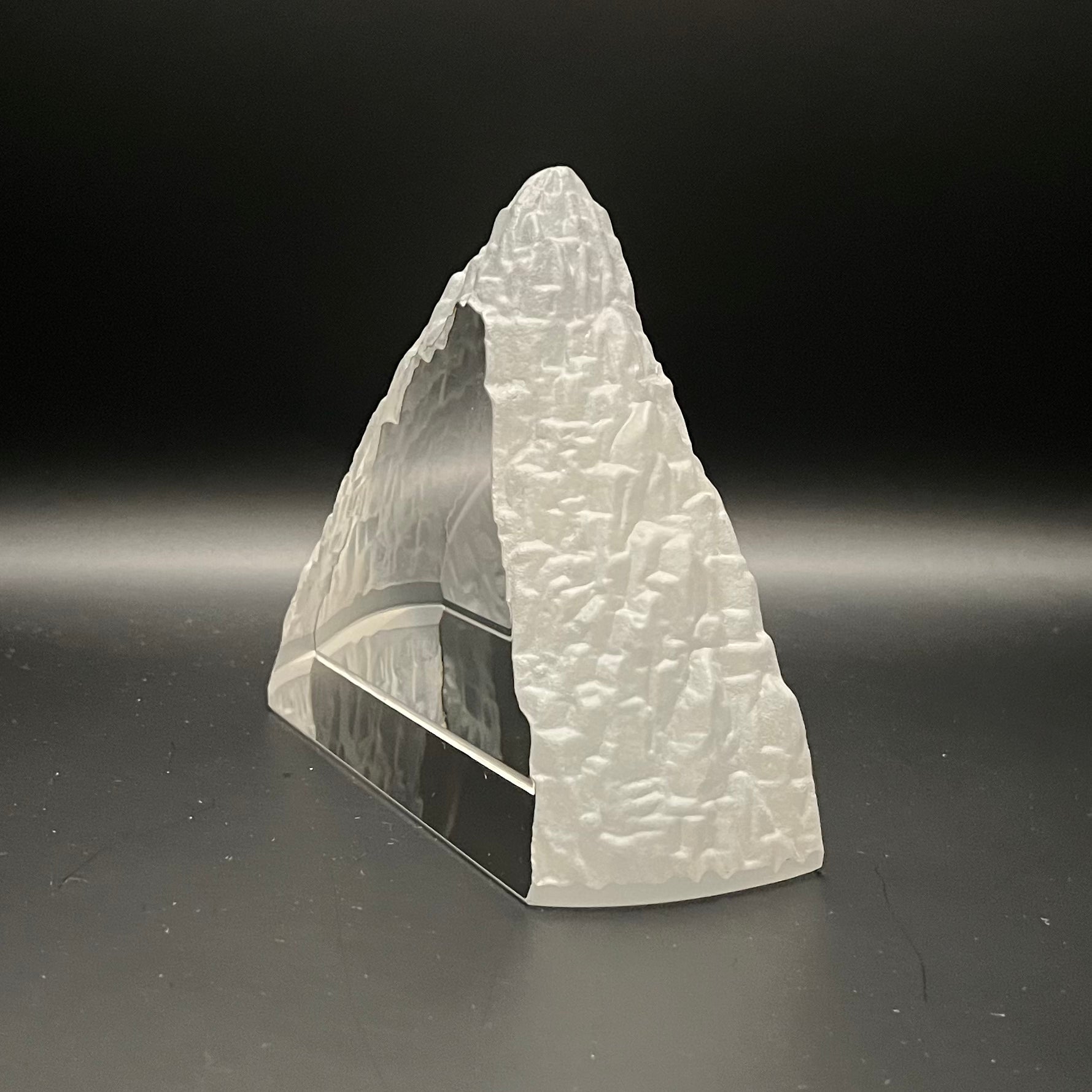 Glass mountain sculpture on a dark gray background