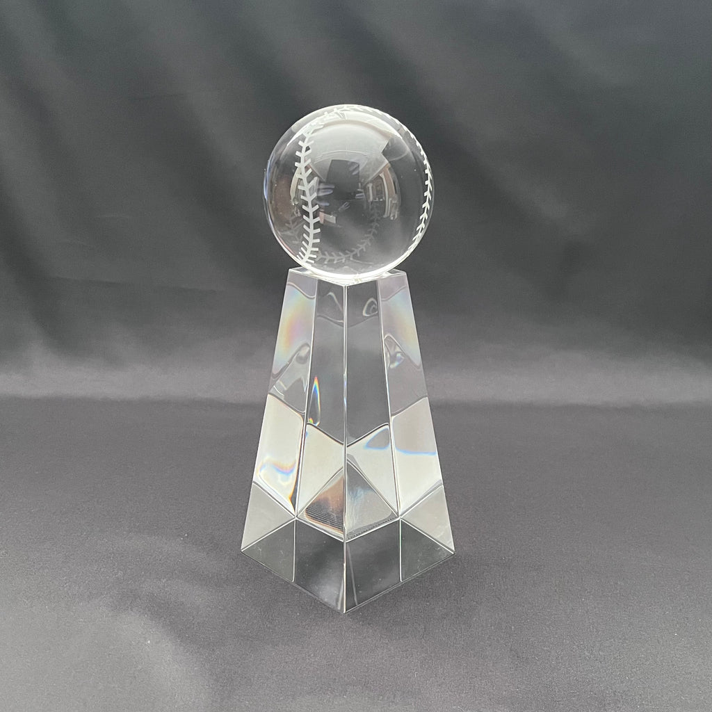 A clear glass trophy featuring a baseball engraved on the top sphere, mounted on a faceted geometric pedestal.